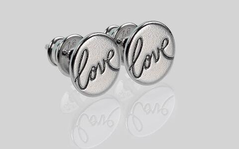 Makroaufnahme von schöne Ohrstecker aus Silber mit Gravur Love und Spiegelung