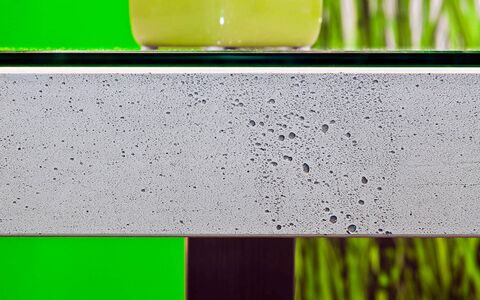 Eine Tischplatte aus Beton auf der eine grüne Vase steht