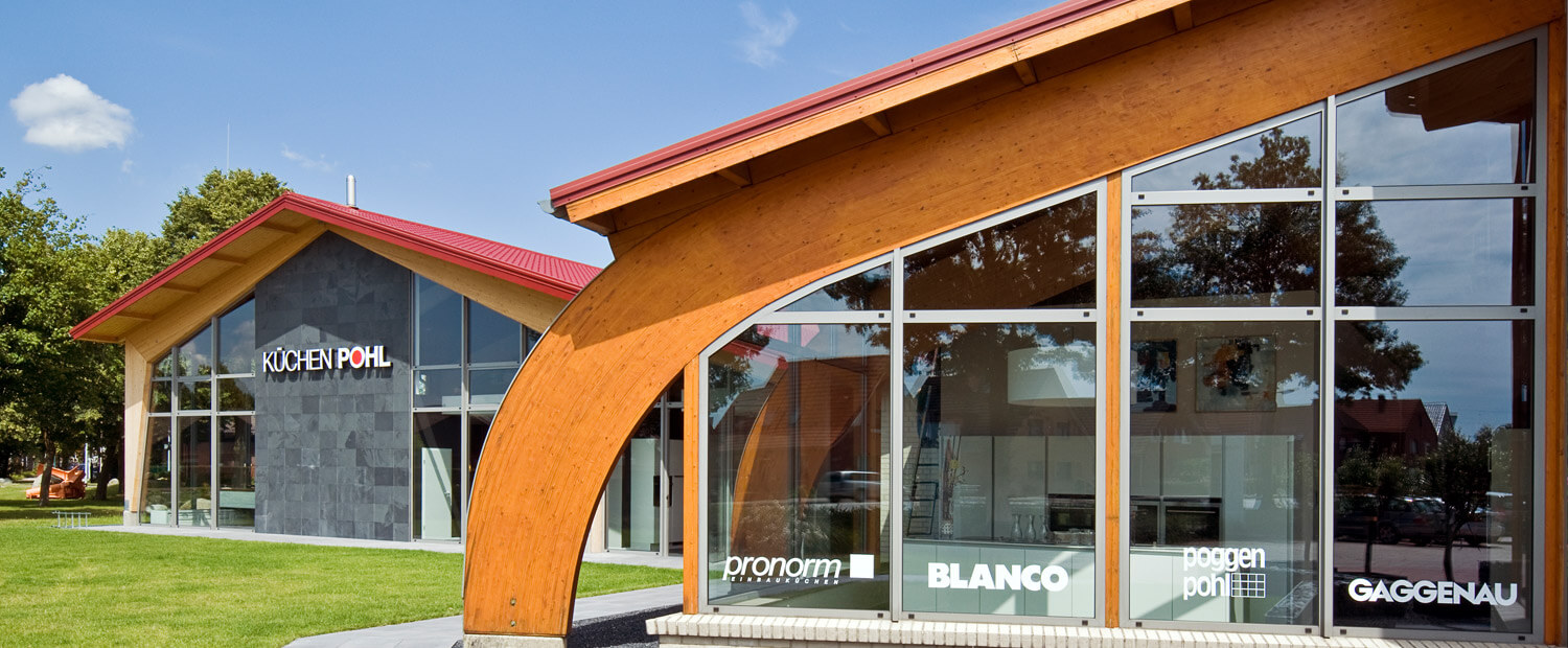 Architekturfotografie des Küchenstudio Pohl im Sommer bei blauem Himmel mit Garten im Vordergrund